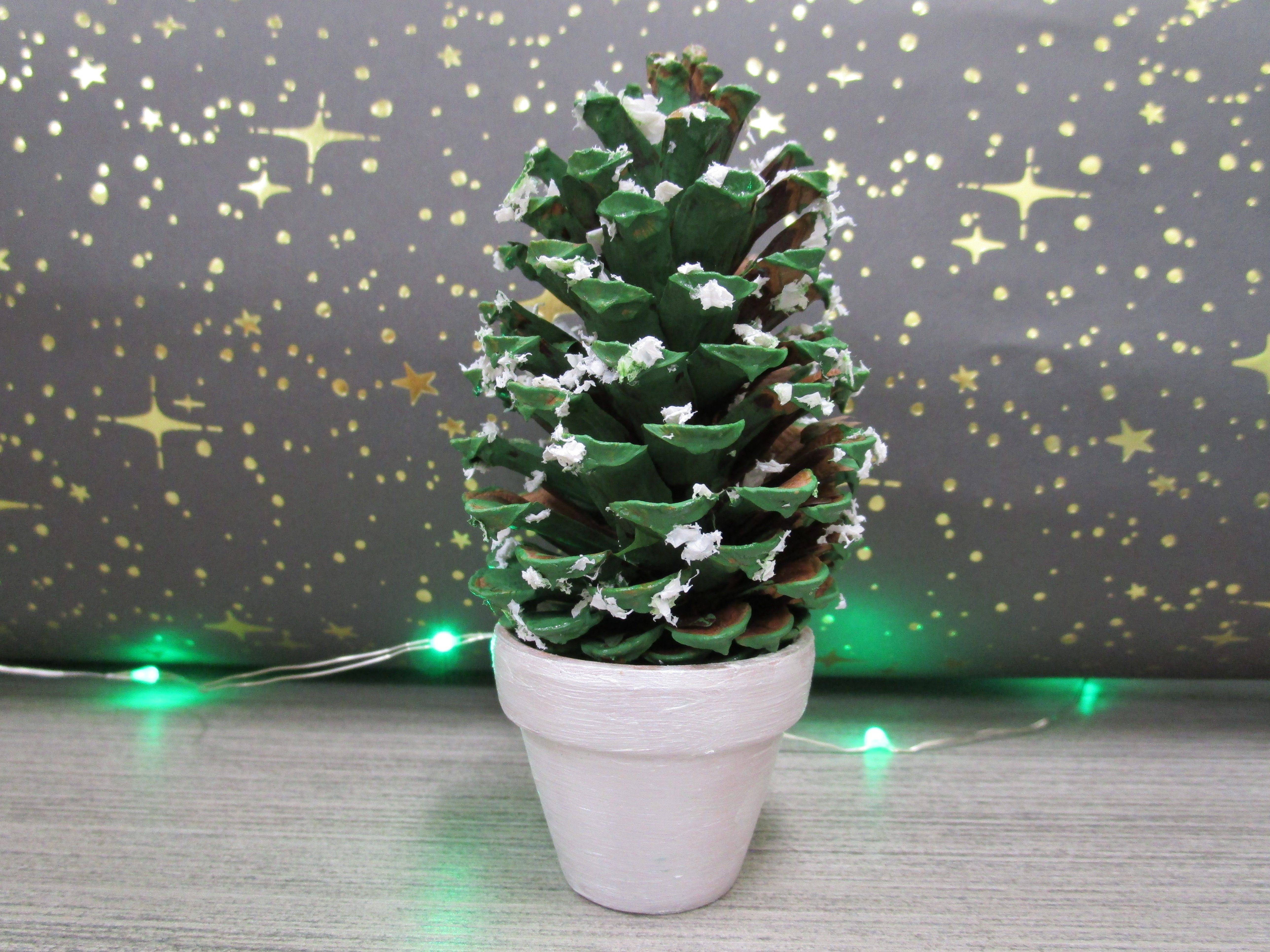 Pinecone painted green in a silver pot with paper snow glued on it
