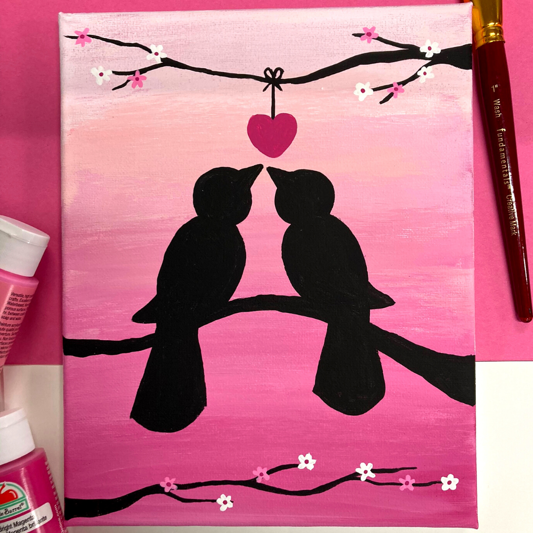 A 8 by 10 canvas painting of two birds and branches silhouetted against a pink gradient. A heart hangs from the flowering branches between them.  