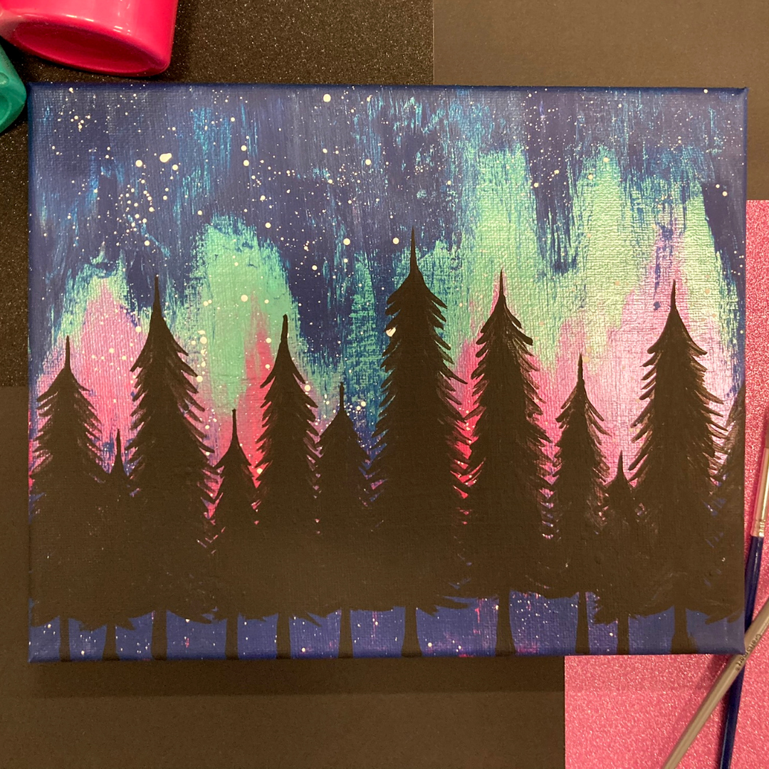 A rectangular canvas with a painting of a night sky featuring a metallic green and pink aurora borealis. Black trees stand in the foreground and white stars are splattered against the sky.