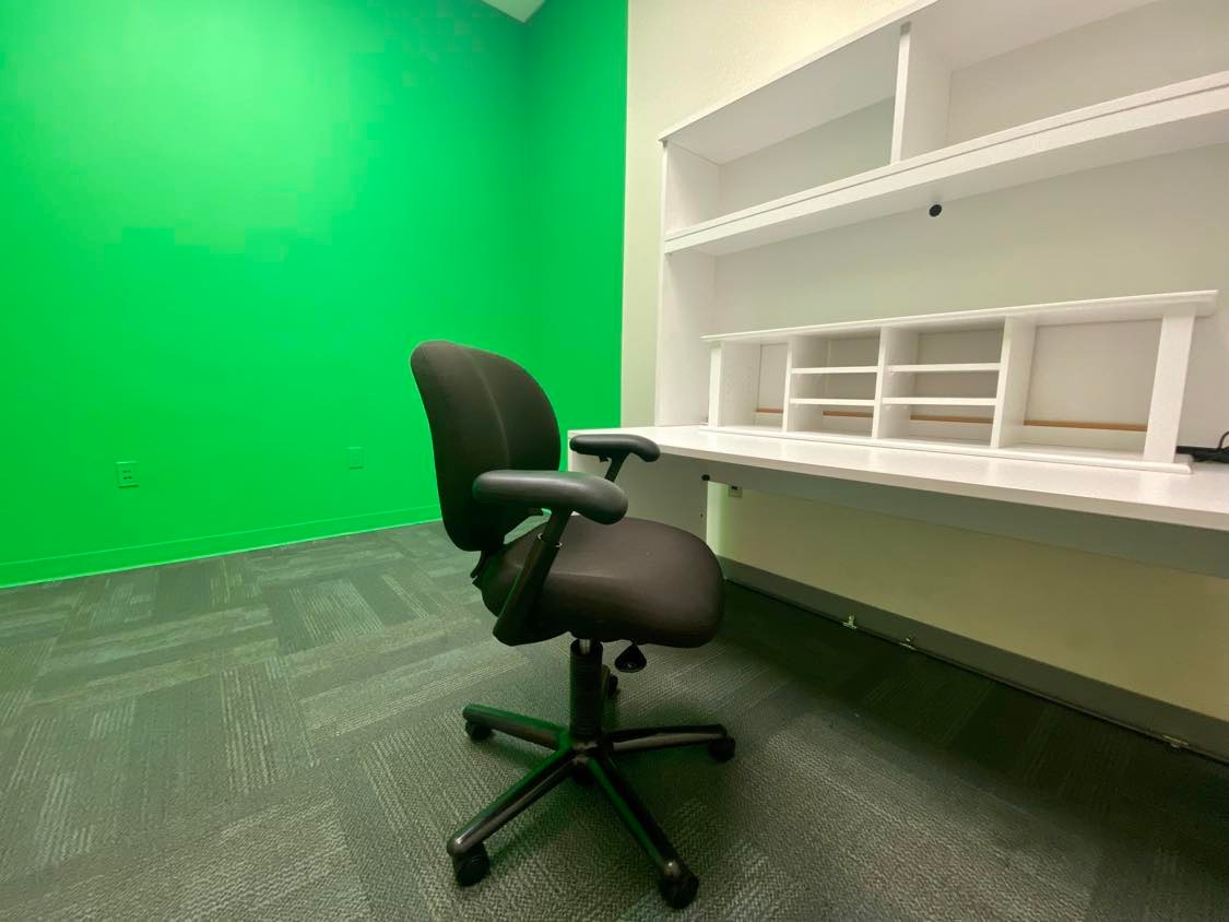 Small room with chair and desk. Green wall.