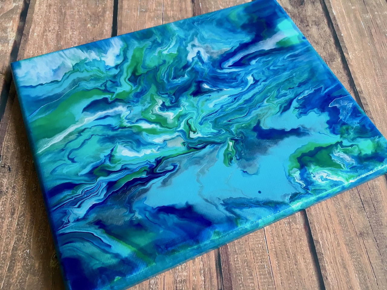 Paint pour image with blue green and white paint. 