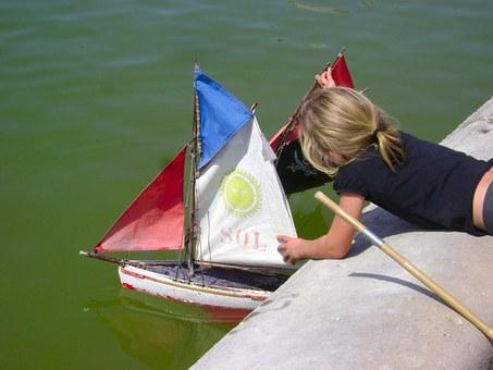 Child trying to sail a toy boat.