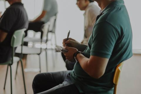 A man taking notes during a presentation