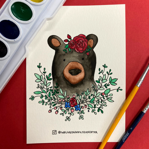A watercolor painting of a bear surrounded by flowers.