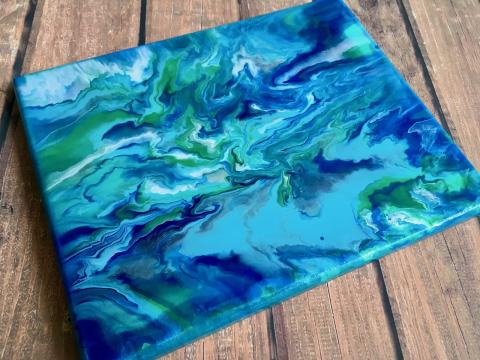 Paint pour image with blue green and white paint. 