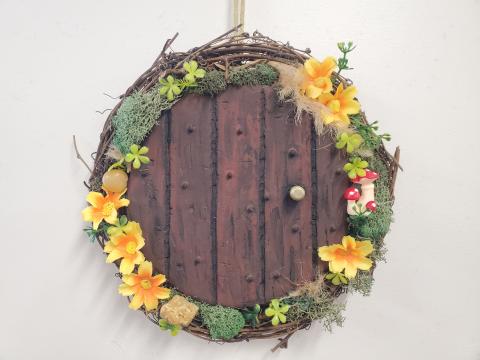 wreath made to look like door with flowers, moss, and rocks around it