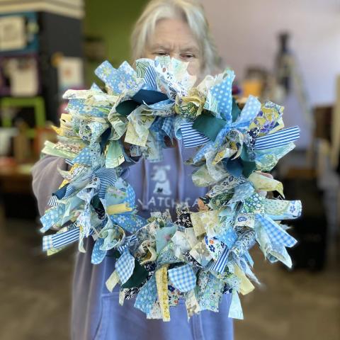 Person holding wreath made out of fabric.