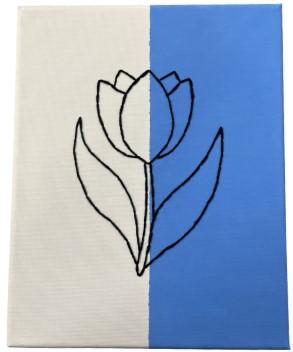Images of an embroidered flower on top of a canvas, one half painted blue the other left white