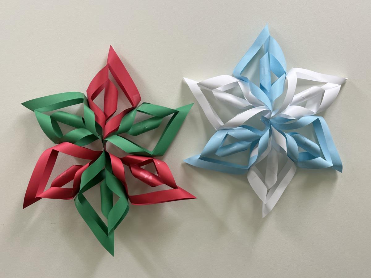 Image of two 3D snowflakes against a wall. One is alternating between white and light blue. The other is alternating between green and red.